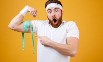 portrait-young-bearded-excited-fitness-man-measuring-biceps