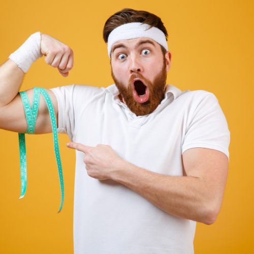 portrait-young-bearded-excited-fitness-man-measuring-biceps